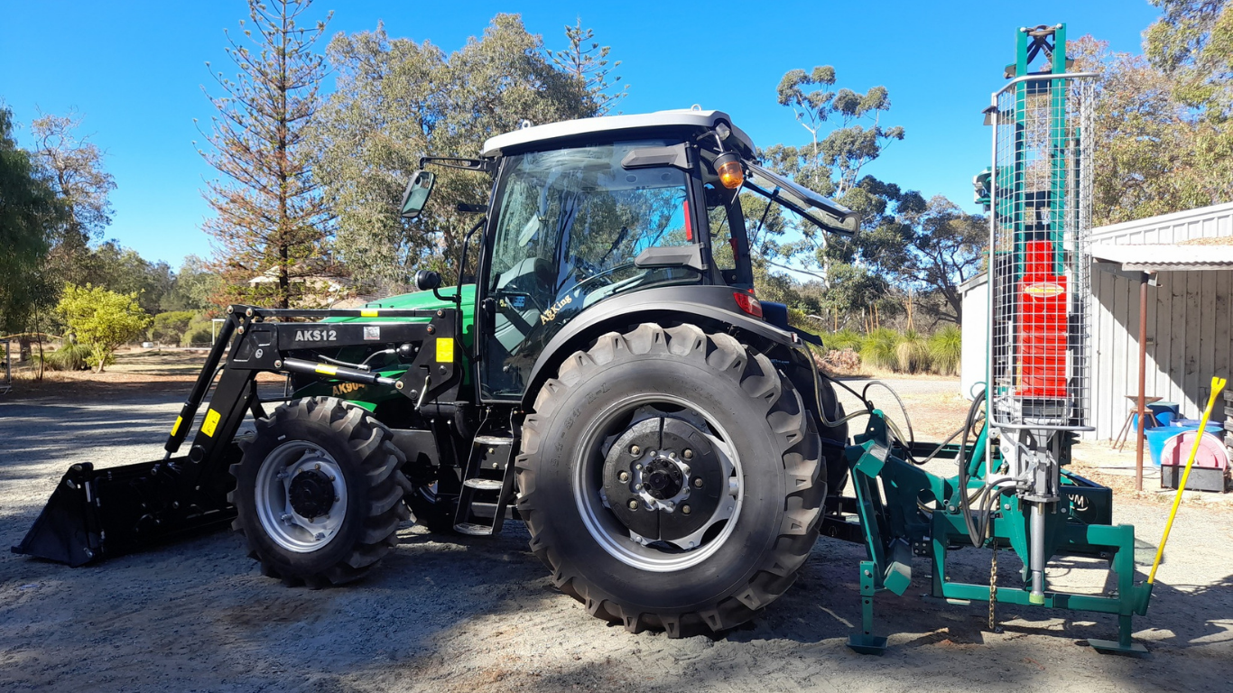 AgKing tractor with front and rear implements leaving shed to prepare for work