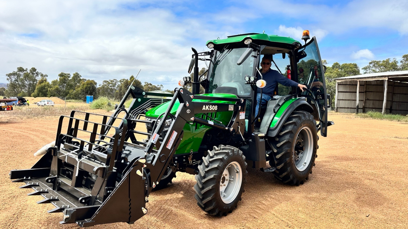 AgKing AK704 cabin tractor fitted with a front-end loader and grapple bucket attachment, operated by a farmer on a Western Australian rural property