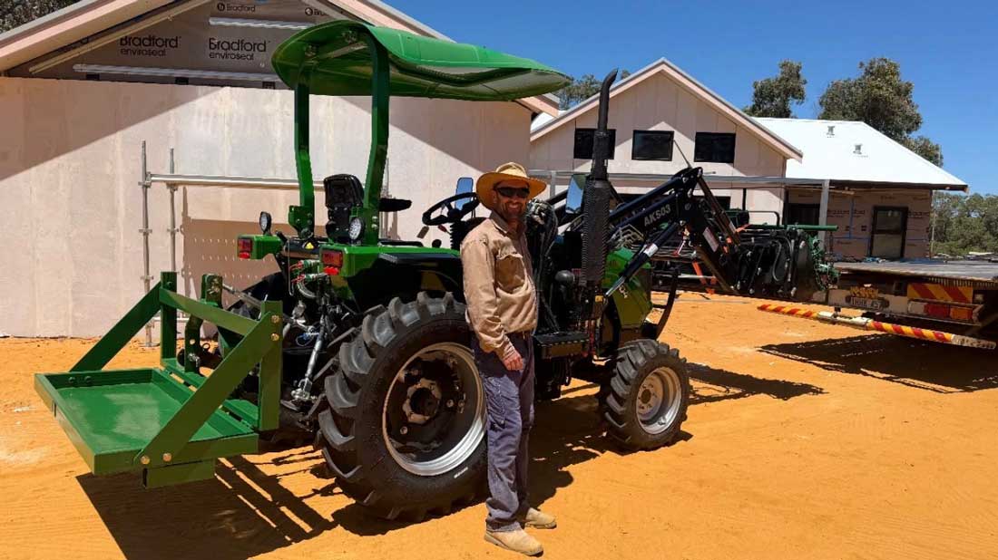 What are the main parts of a tractor Compact tractor with a front-end loader bucket parked at a house build site, operator standing beside the machine.