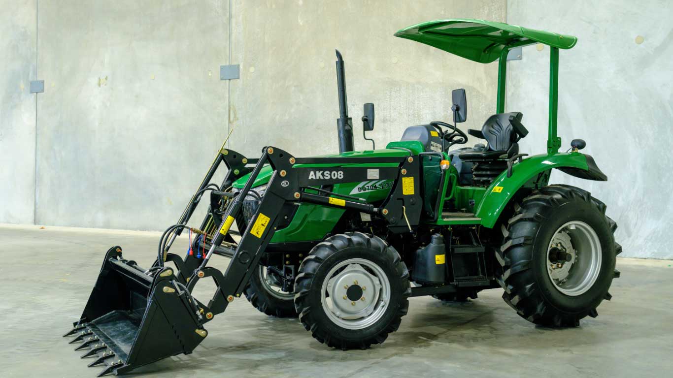 Loaders, hitches and attachments AgKing AK508 tractor with a canopy (no cab) and a front-end loader fitted with fork tines, photographed indoors.